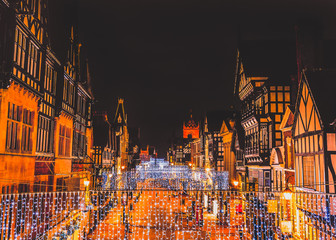 Eastgate Street Chester, UK at night with Christmas lights hanging from the impressive Tudor black and white buildings