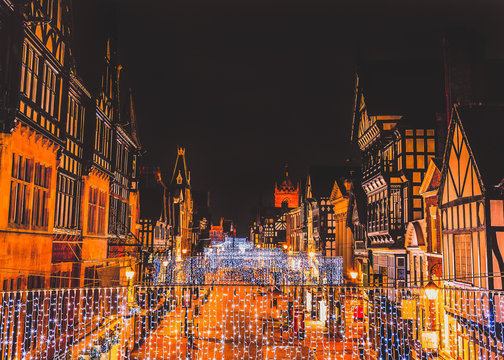 Eastgate Street Chester, UK at night with Christmas lights hanging from the impressive Tudor black and white buildings
