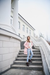 Beautiful young girl in white sweater and pink jacket walking in the Park.