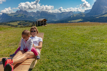 Mother and baby daughter enjoying a sunlounger in the fresh air on Seiser Alm South Tyrol Italy