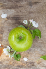 Fresh sweet juicy green apples with flowers on a wooden background