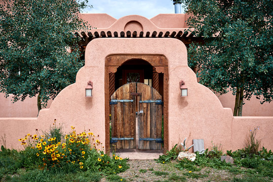 an adobe building with a wooden gate and wall