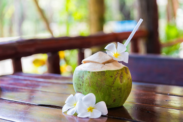 Fresh coconut cuts with tropical palm leaves and white frangipani flowers