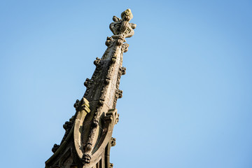 Ornate pinnacle on a church spire pointing up into a blue sky