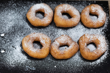 Homemade donuts with icing sugar powder on wooden background
