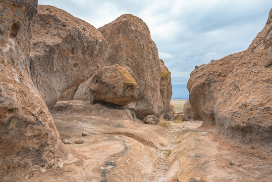 Path Along A Small Wash Through Huge Pink Boulders With Dark Clouds Looming Overhead