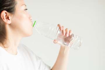 A woman drinking water from plastic bottle.