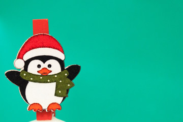 Penguin in a red hat and scarf stands on a green background. Background for new year greeting card. Template for post about Christmas