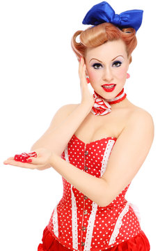 Young beautiful pin-up girl in vintage polka dot corset with red dice in her hand