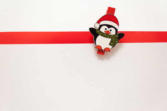 Penguin in a red hat and scarf on a white background. White background with red stripe. Background for new year greeting card. Template for post about Christmas