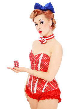Young beautiful pin-up girl in vintage polka dot corset with red dice in her hand