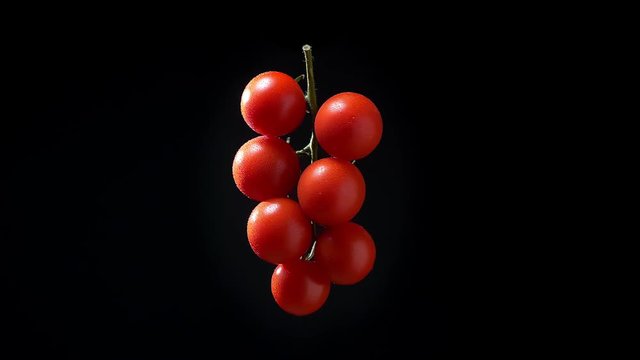 Illustration of bunch of red tomatoes slowly spinning counterclockwise on black background.