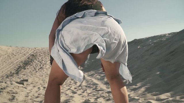 Sexy young girl dancing twerk at the beach Hot girl with attractive body shakes her butt Pretty girl dances passionately Cute female with shirt tied at the waist slow motion Shooting from behind