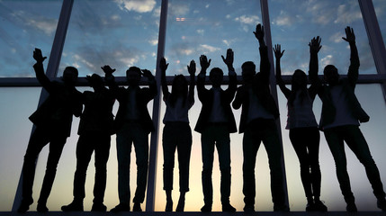 silhouette of a group of business people raising their hand