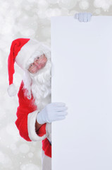 Santa Claus peeking out from behind a large balnk sign