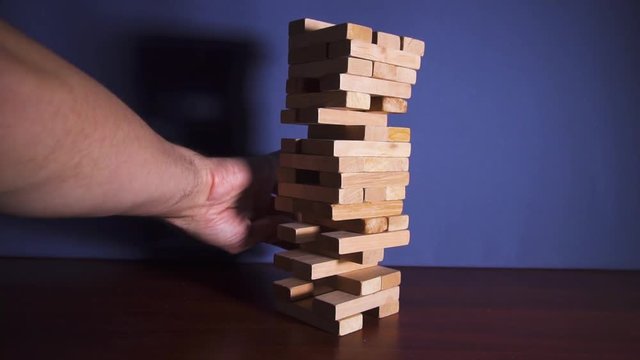 Wooden game tower falling on the table in slow motion