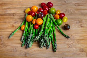 Green asparagus and colorful cherry tomatoes on wooden surface