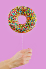 Donut in hand on a pink background