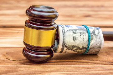 Gavel with rolled money on the table. Close up.