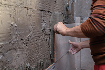 Gluing tiles on the wall. Laying tiles on the wall.  Worker installing big ceramic tiles on the walls