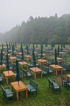 Acadia National Park, Maine, USA: Rows of tables and benches and folded umbrellas on a lawn, in the rain, at the Jordan Pond House.