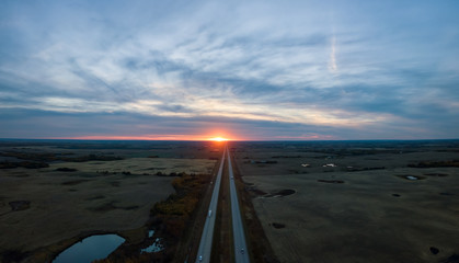 Aerial panoramic view of the Highway in the Prairies during a vibrant cloudy sunset. Taken East of Edmonton, Alberta, Canada. - obrazy, fototapety, plakaty