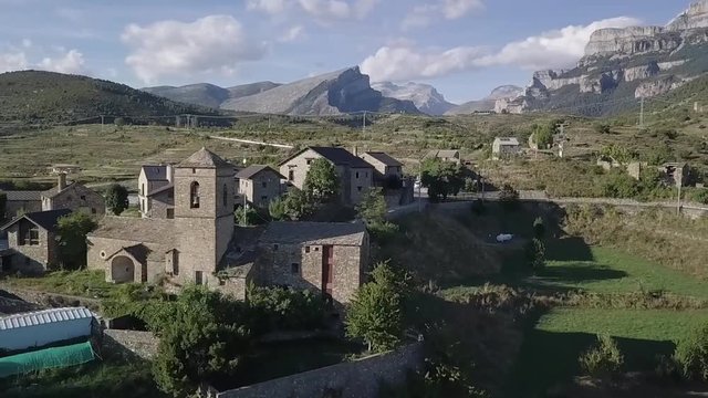 Authentic mountain village, drone shot flying over revealing, on a sunny day.?located in the middle of the pyrenees.