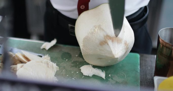 Bartender cutting open a coconut for a refreshing drink 