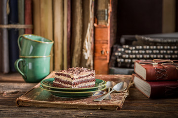 Sweet chocolate cake with coffee, books and typewriter