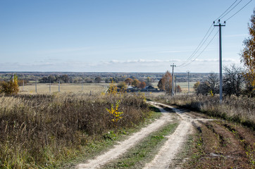 Fototapeta na wymiar Countryside Dirt Road. The long and winding rural path crosses the hills.