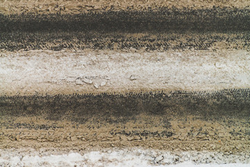 Snowy road close up. Car track in dirty snow. Track of tyres. View from above on highway. Textured winter realistic background with copy space. Abstract minimalist snowy weather texture.