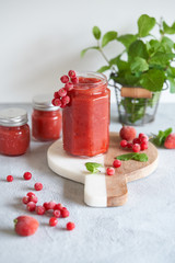 Pink strawberry puree with red currant and mint in a glass jar. Gray background.