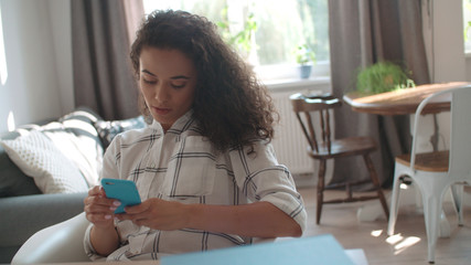 Young woman using mobile phone at home.