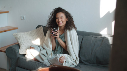 Portrait of smiling woman drinking coffee or tea at home.