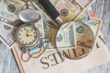 Fototapeta na wymiar Pocket watch, American dollars and a magnifying glass
