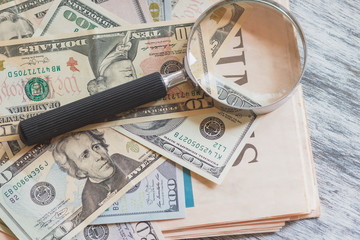 Obraz na płótnie Canvas American dollars and a magnifying glass, top view