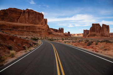 Landscape view of a Scenic road in the red rock canyons during a vibrant sunny day. Taken in Arches National Park, located near Moab, Utah, United States.