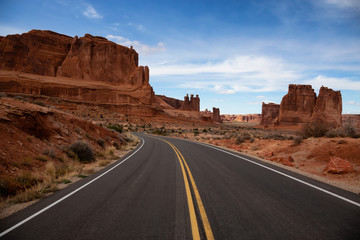 Landscape view of a Scenic road in the red rock canyons during a vibrant sunny day. Taken in Arches National Park, located near Moab, Utah, United States.