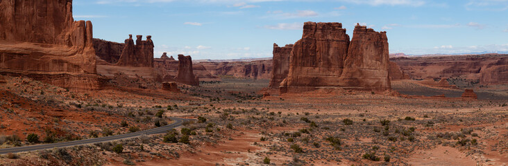 Panoramic landscape view of a Scenic road in the red rock canyons during a vibrant sunny day. Taken in Arches National Park, located near Moab, Utah, United States.
