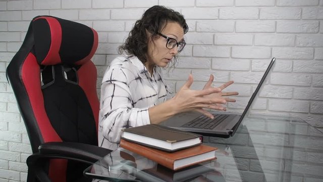 Woman at a loss. A woman at the workplace is nervous looking into a laptop.