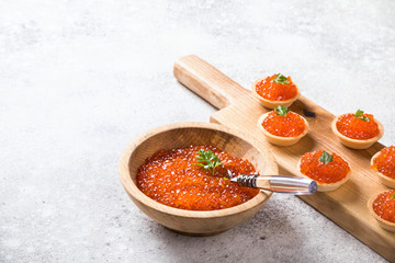  holidays composition. Red Salmon Caviar in wooden bowl, Tartlets Festive Appetizer  on  gray background.Copy space for Text.