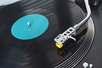 Turntable vinyl record player on the background of a sunset over the lights city. Sound technology for DJ to mix & play music. Black vinyl record. Vintage vinyl record player. Needle on a vinyl record