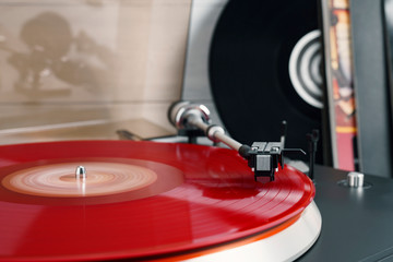 Fototapeta na wymiar Vinyl record turntable rotate and black headphones on a white background. Equipment for the disc jockey. Sound technology for DJ to mix and play music. Red vinyl plate. Vinyl records with covers