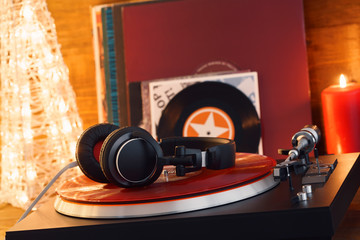 Turntable player with black headphones on the background of a stack of audition records and a...