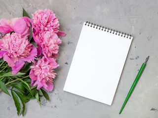 note book with pink peonies on a stone background, copy space for your text top view and flat lay style.
