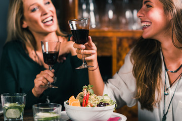 Healthy Eating. Female Friends in Vegetarian Restaurant Eating, Drinking Wine and Having Fun.