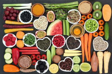 Health food for clean eating concept including grains, seeds, coffee, supplement powders, fresh fruit, vegetables and dairy. High in antioxidants, protein, anthocyanins, vitamins and dietary fibre.  