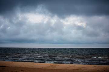 storm clouds forming over clear sea beach with rocks and clear sand