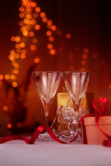 glasses of wine/ champagne glasses with Christmas gift box in craft paper with red ribbon.