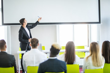 Rear view of Audience in the conference hall or seminar meeting which have Speakers on the stage,...